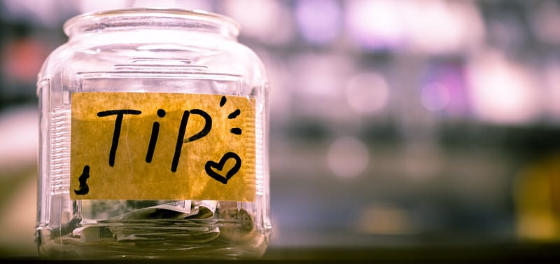 Image of a glass jar used for tips, showing money already put inside.